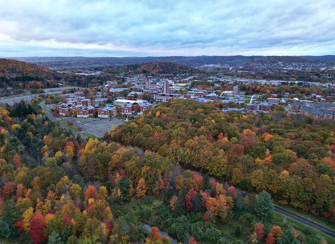 Vestal, NY - Aerial View of University Buildings Surrounded by Fall Colored Trees and Mountains in Vestal New York